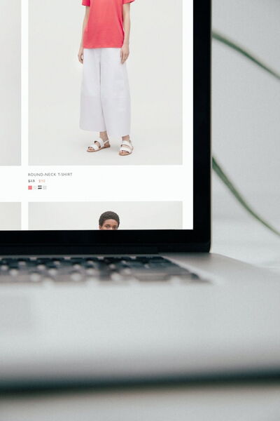 Rechter Teil eines Laptops, der ein Onlineshop für Damenbekleidung zeigt. Ein Bild mit Frau in weißer Hose und rotem T-Shirt ist rechts unten in der Ecke zu sehen.
