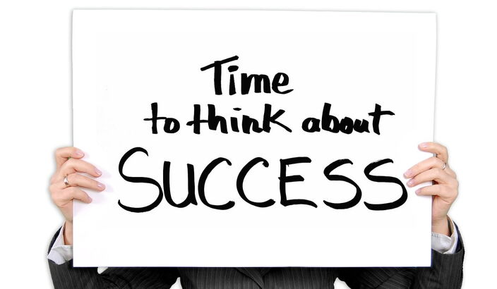 Person hebt weißes Schild vor den Körper "Time to think about success"