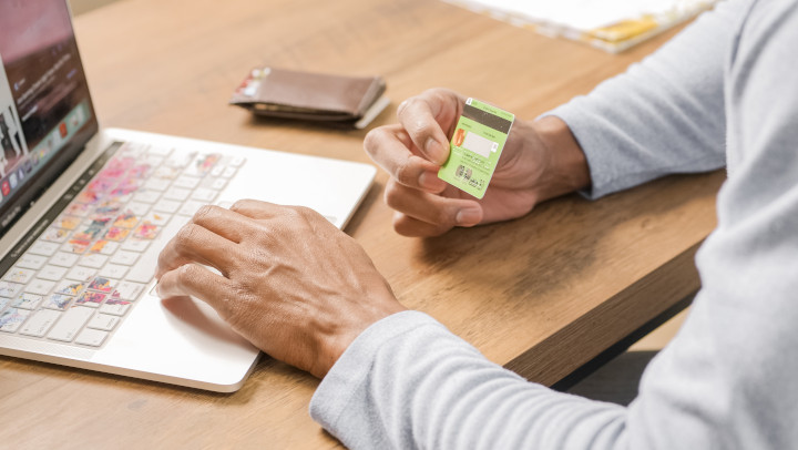 Shopping Onlineshop für E-Commerce erstellen lassen - Mann sitzt vor einem Laptop und hält die Kreditkarte in der rechten Hand