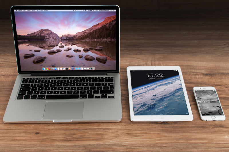 Notebook, Tablet und Smartphone liegen auf einem Holztisch